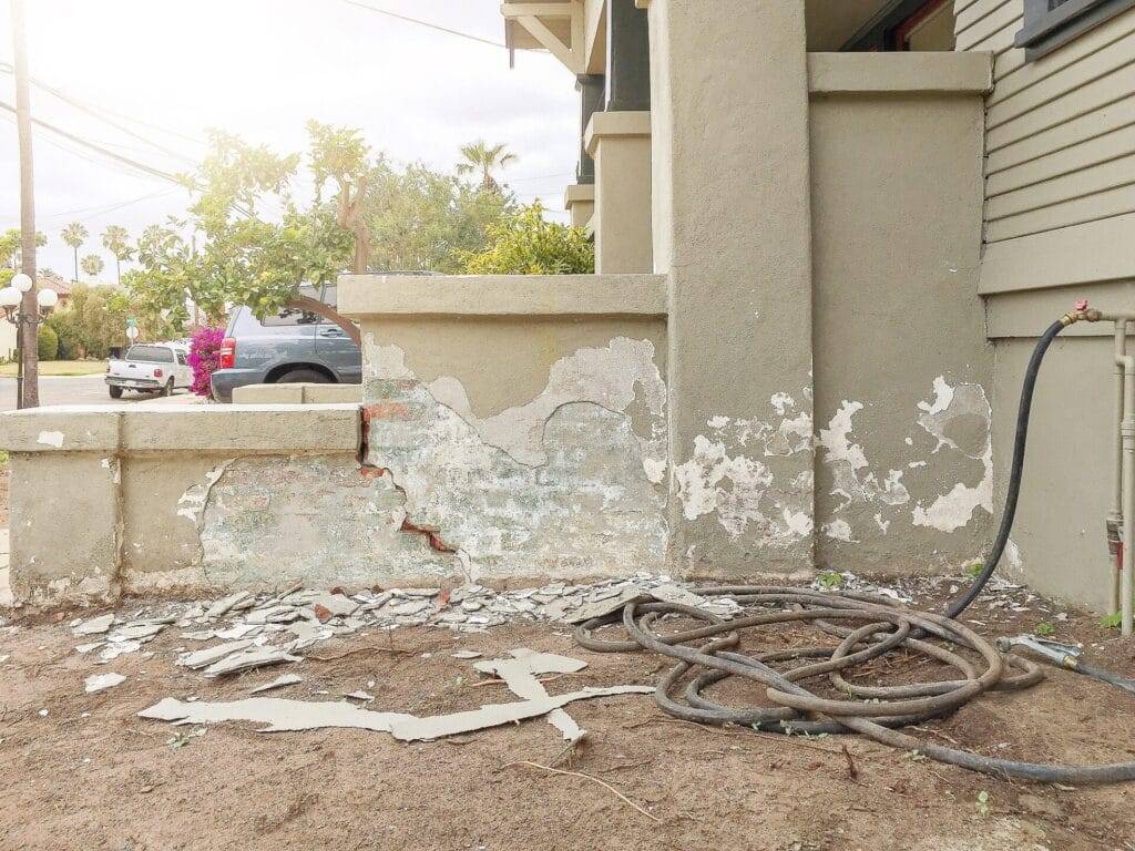 Damaged stucco on the side of entry door stairs